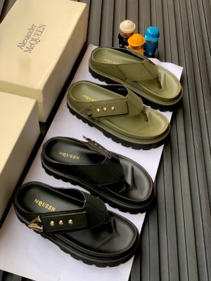 Black and olive green Alexander McQueen leather thong sandals with chunky platform sole and buckle detail displayed on boxes.