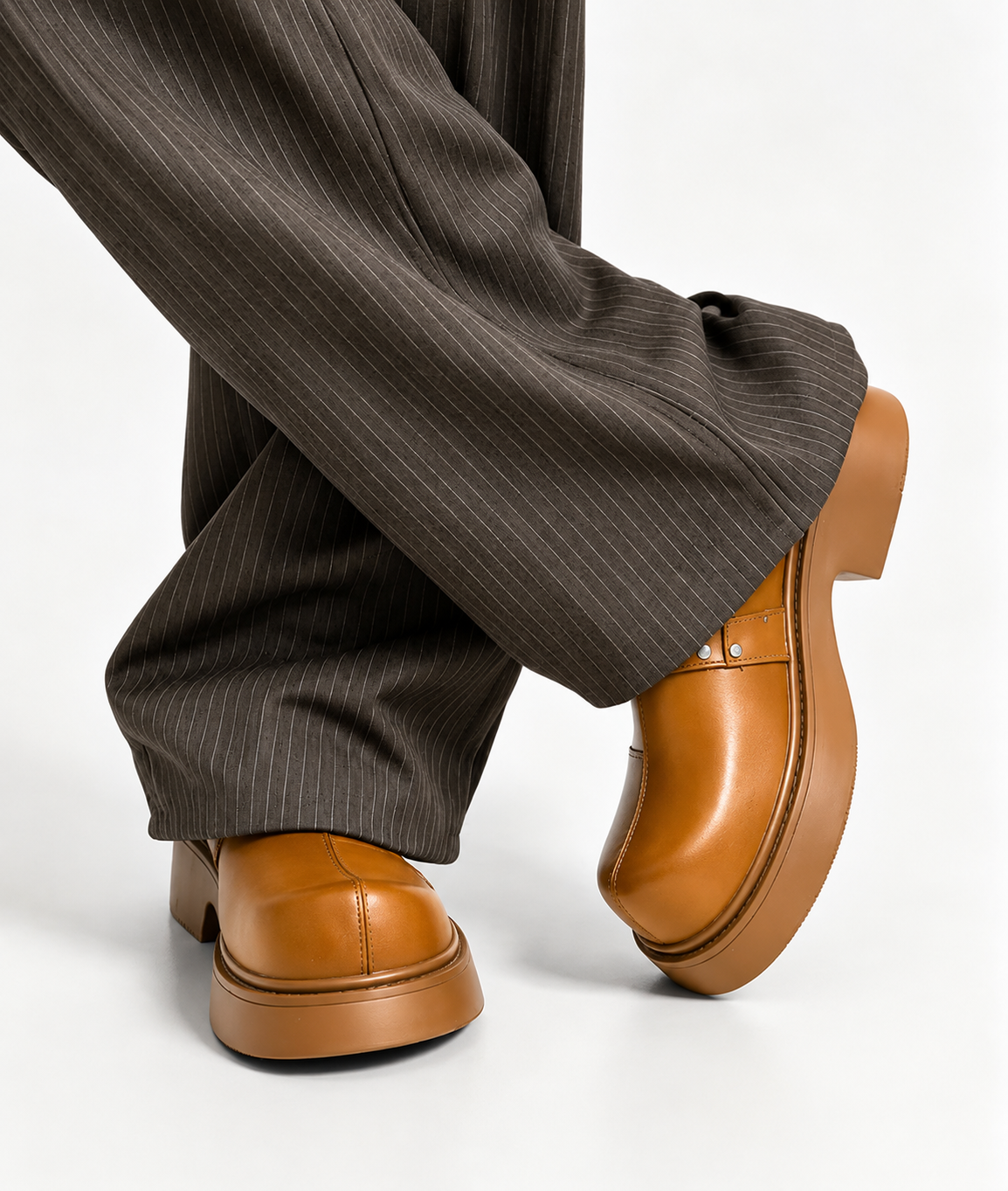 Premium leather monk-strap loafers Men's luxury leather monk-strap loafers with chunky black platform soles and silver hardware accents being held by hand next to white trousers.