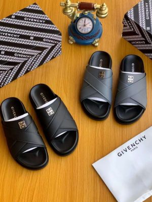 A pair of men's luxury black leather slides and a pair of grey leather slides, displayed on a wooden surface with premium packaging, showcasing their sleek design and premium material.