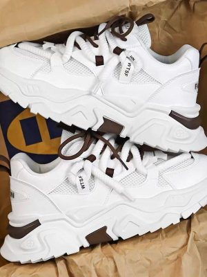 A pair of men's luxury grey chunky sneakers with lime green accents, displayed in a box with brown paper, showcasing their bold design and thick, cushioned sole.