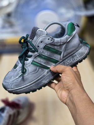 men's luxury grey suede sneaker with green stripes and laces, showcasing its premium texture and chunky sole design.