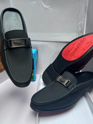 Salvatore Ferragamo brown perforated leather loafer with Gancini bit buckle, held by hand showcasing craftsmanship