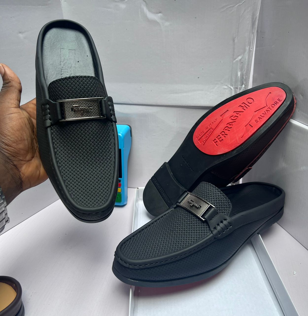 Salvatore Ferragamo Perforated Leather Slip-On Salvatore Ferragamo brown perforated leather loafer with Gancini bit buckle, held by hand showcasing craftsmanship