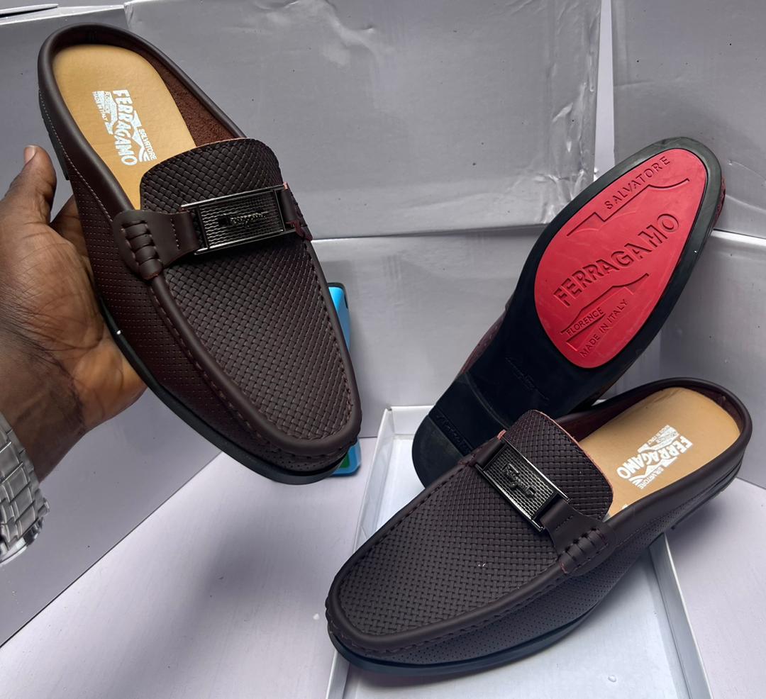 Salvatore Ferragamo Perforated Leather Slip-On Salvatore Ferragamo brown perforated leather loafer with Gancini bit buckle, held by hand showcasing craftsmanship