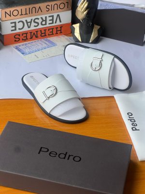Black Pedro leather slides with silver buckle hardware and tan sole displayed with Pedro box and dust bag alongside luxury brand boxes.