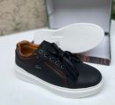 Black Lacoste leather sneakers with brown accents and white sole displayed with shoe box.