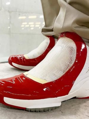 White and red Air Jordan 11 "Win Like '82" sneakers with patent leather mudguard and translucent outsole displayed on shoe box.