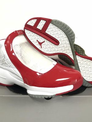 White and red Air Jordan 11 "Win Like '82" sneakers with patent leather mudguard and translucent outsole displayed on shoe box.