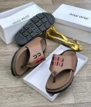 Brown Miu Miu thong sandals with black and red embroidered logo and chunky black treaded sole displayed in white box with gold decor.