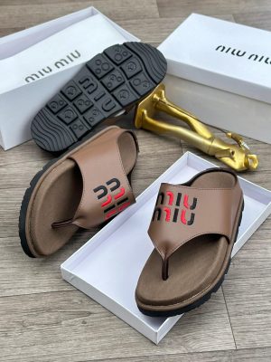 Brown Miu Miu thong sandals with black and red embroidered logo and chunky black treaded sole displayed in white box with gold decor.