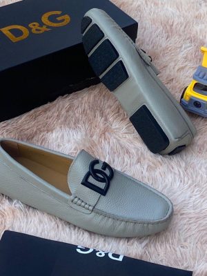 Navy blue D&G pebbled leather driving loafers with black hardware and rubber sole displayed on fluffy rug with D&G box and toy truck.