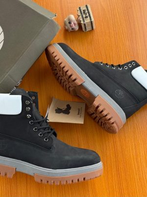 Black Timberland premium boots with white collar flap and chunky gum sole displayed with branded box and tag.