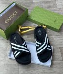 Gucci men's black and white Web stripe slide sandals with rubber footbed, displayed with green Gucci box and gold decorative item on wooden floor.