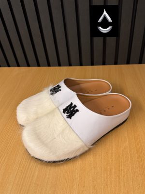 AMIRI luxury fur slide mules in white, black, and brown with authentic leather upper, plush fur detailing, signature AM logo, and cushioned sole displayed with original black AMIRI box