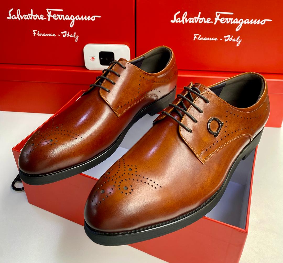 Salvatore Ferragamo tan leather brogue oxfords Men's tan Salvatore Ferragamo leather brogue oxfords with Gancini hardware and rubber sole, displayed with branded red shoeboxes on white surface.