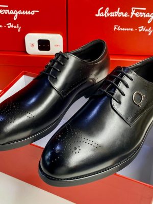 Men's tan Salvatore Ferragamo leather brogue oxfords with Gancini hardware and rubber sole, displayed with branded red shoeboxes on white surface.