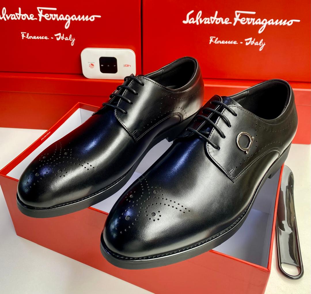 Salvatore Ferragamo tan leather brogue oxfords Men's tan Salvatore Ferragamo leather brogue oxfords with Gancini hardware and rubber sole, displayed with branded red shoeboxes on white surface.