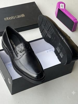 Men's black Roberto Cavalli high-gloss leather penny loafers with quilted vamp detail and ridged sole, displayed in a branded black shoebox.