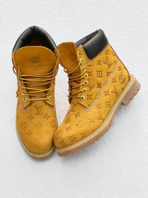 A pair of men's luxury tan designer boots with a distinctive pattern, displayed on orange boxes with branded packaging, showcasing their bold design and thick, cushioned sole. Copy Ask Explain Translate(en-US)