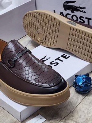 Brown Lacoste leather loafers with embossed crocodile texture, metal horsebit hardware, and chunky tan platform sole displayed with white Lacoste boxes