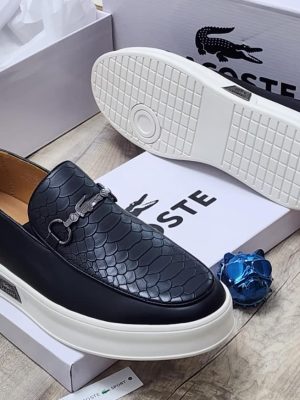 Brown Lacoste leather loafers with embossed crocodile texture, metal horsebit hardware, and chunky tan platform sole displayed with white Lacoste boxes