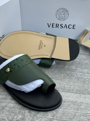 Olive green Versace leather slides with gold Medusa head logo and black sole displayed with white Versace boxes.