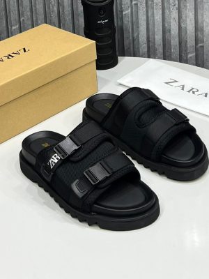 Zara men's taupe tactical slide sandals with double adjustable straps, white logo branding, and chunky black rubber lug sole, displayed with branded box and dust bag on white surface.