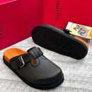 Black leather Valentino Garavani slides with buckle strap detail, orange footbed, and chunky black sole - luxury men's sandals