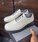 Cream leather formal lace-up shoes with black laces and layered sole displayed on a grey box.