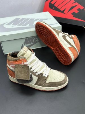 Brown and orange Nike Air Jordan 1 High sneakers with cream base and extra laces displayed with Nike box.