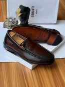 Brown Berluti leather loafers with crocodile-embossed vamp and gold heel stud displayed with white Berluti box and wooden shoe tree.