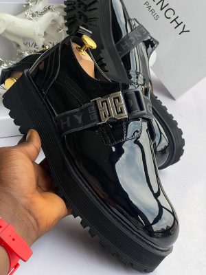 Black Givenchy patent leather loafers with 4G buckle strap and chunky sole displayed with white Givenchy box and horse decor.