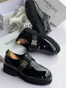 Black Givenchy patent leather loafers with 4G buckle strap and chunky sole displayed with white Givenchy box and horse decor.
