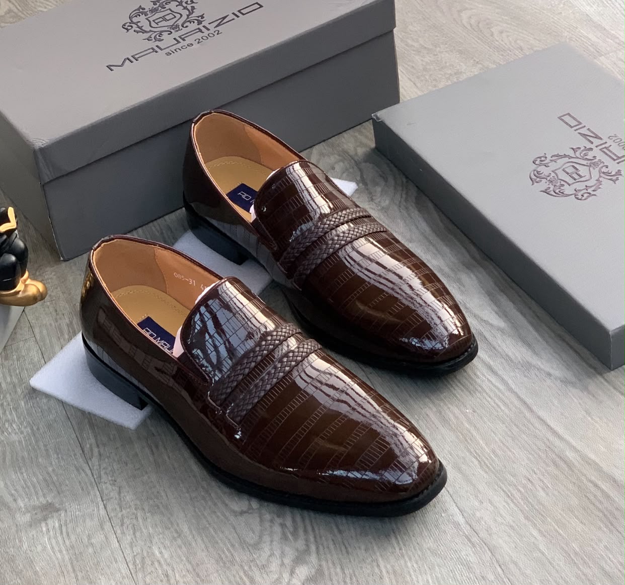 Genuine burgundy ostrich leather horsebit loafers Men's burgundy genuine ostrich leather horsebit loafers with square toe, gold hardware, and rubber sole, displayed on grey wood floor with branded shoebox.