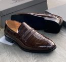 Men's burgundy genuine ostrich leather horsebit loafers with square toe, gold hardware, and rubber sole, displayed on grey wood floor with branded shoebox.
