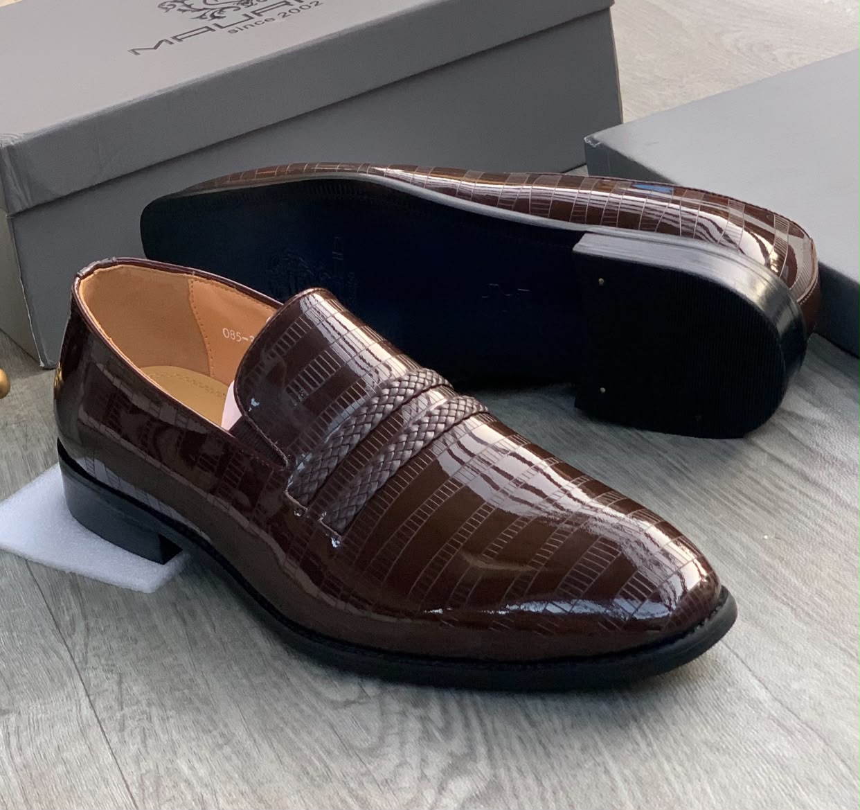 Genuine burgundy ostrich leather horsebit loafers Men's burgundy genuine ostrich leather horsebit loafers with square toe, gold hardware, and rubber sole, displayed on grey wood floor with branded shoebox.