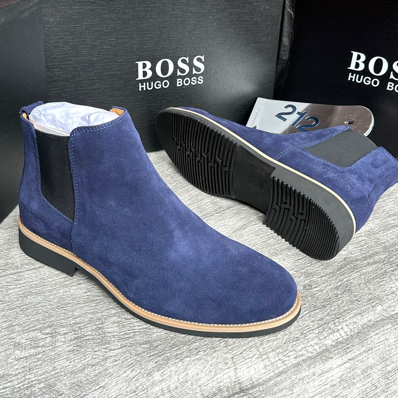 Hugo Boss navy suede Chelsea boots featuring elastic side panels and natural welt stitching. A textured alternative to leather that balances professional polish with smart-casual versatility. Sourced from verified suppliers with a 7-day return guarantee.