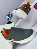 Alt Text: Black knit Tommy Hilfiger slip-on sneakers with white platform sole and red, white, blue flag stripe - luxury men's casual shoes.