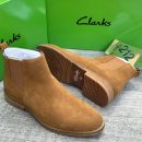 Tan Clarks suede Chelsea boots with ridged rubber sole displayed with green Clarks box.
