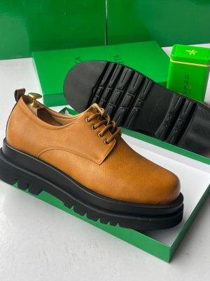 Bottega Veneta men's tan pebbled leather chunky derby shoes with thick black lug sole, displayed in signature green shoebox with branded tin.