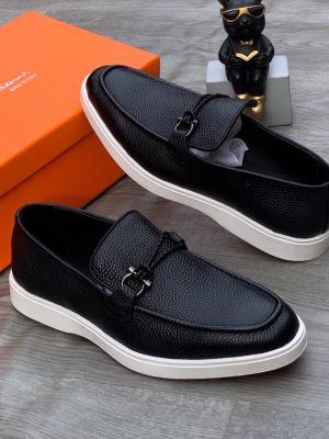 Santoni men's black pebbled leather loafer sneakers with braided strap, gunmetal hardware, and white rubber sole, displayed with orange branded shoebox on grey wood floor.