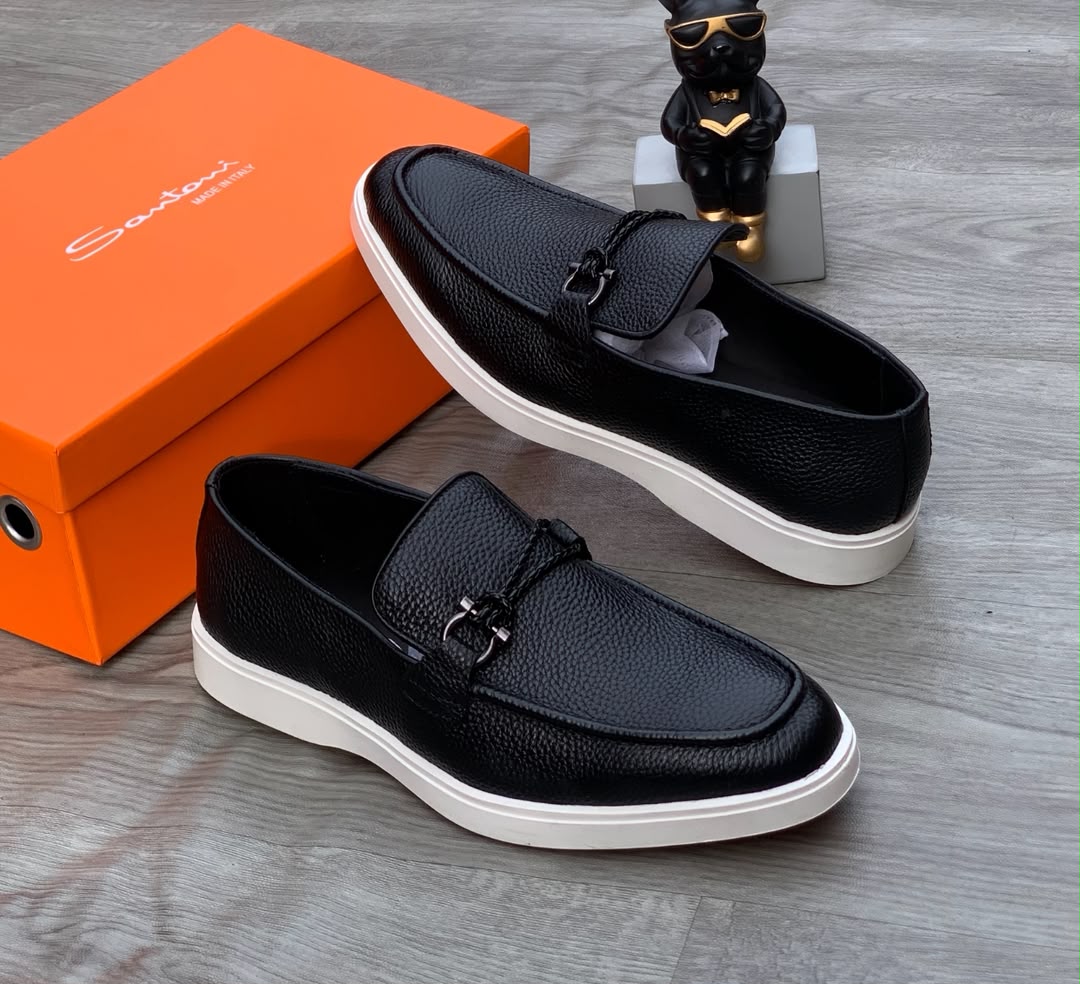 Santoni black pebbled leather loafer sneakers Santoni men's black pebbled leather loafer sneakers with braided strap, gunmetal hardware, and white rubber sole, displayed with orange branded shoebox on grey wood floor.