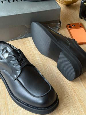 FDCP men's black leather derby shoes with tonal laces and thick black rubber sole, displayed on wooden surface with grey branded shoebox and orange phone.