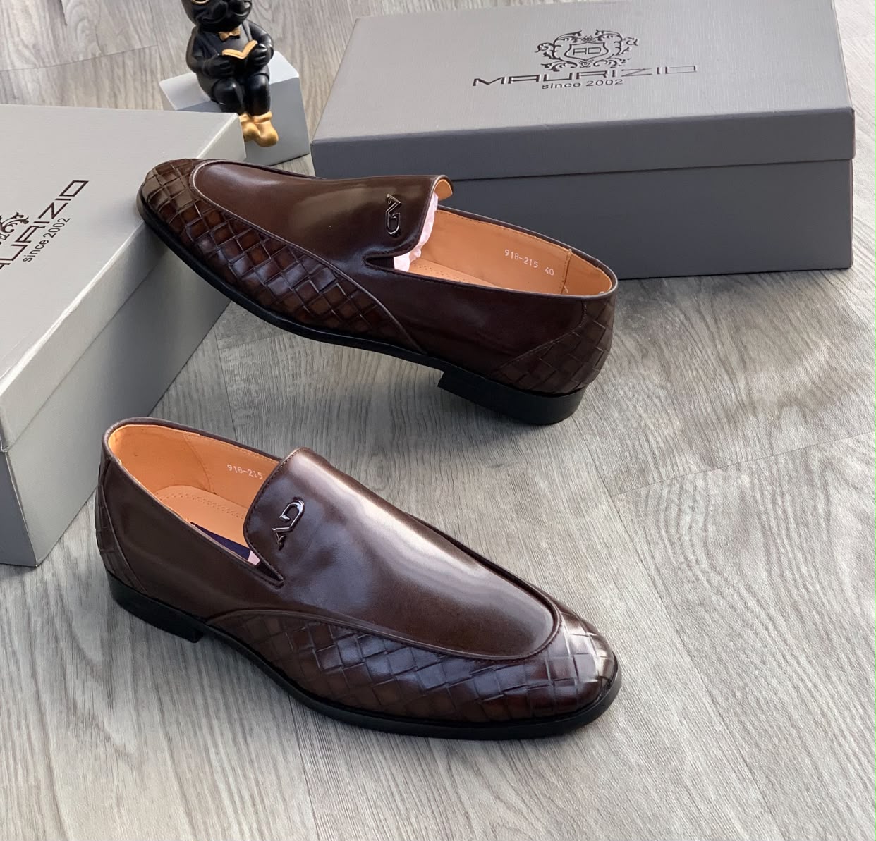 Maurizidio chocolate brown woven leather loafers Men's chocolate brown Maurizidio woven leather loafers with metallic logo and black rubber sole, displayed on grey wood floor with branded shoebox.