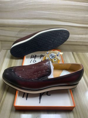 Burgundy leather hybrid loafers with crocodile embossed vamp and white chunky sole displayed in orange box with jewelry.