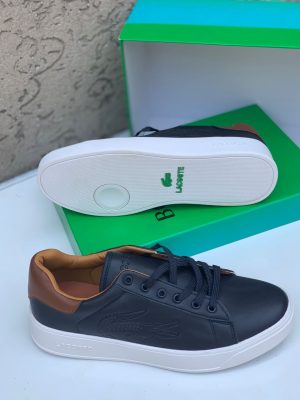 Black Lacoste leather sneakers with white sole and tan heel tab displayed with green Lacoste box.