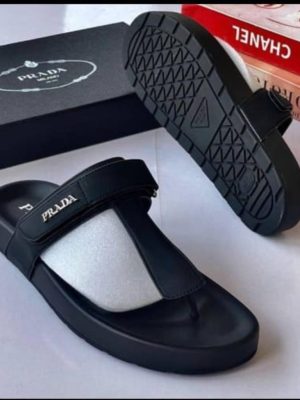 Black Prada leather thong sandals with adjustable ankle strap and chunky geometric tread sole displayed with Prada box.