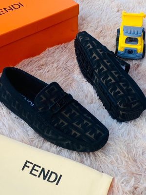 Black Fendi FF monogram driving loafers with rubber sole displayed on fluffy rug with orange Fendi box and toy truck.