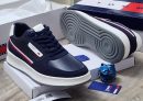 Navy blue Tommy Hilfiger leather sneakers with white sole and red stripe detail displayed with Tommy box and blue skull decor.