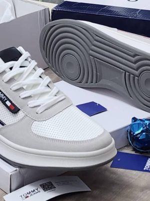 Navy blue Tommy Hilfiger leather sneakers with white sole and red stripe detail displayed with Tommy box and blue skull decor.